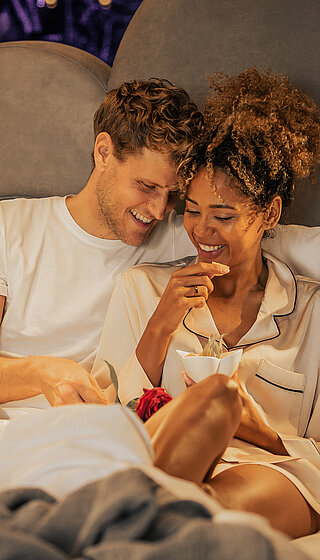 Couple enjoying breakfast in bed in a Spa Deluxe double room at the Hotel Winzer