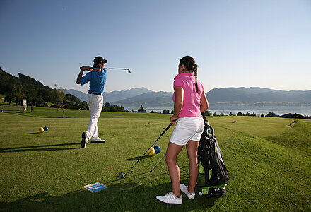 Couple playing golf by Lake Attersee in the Salzkammergut region