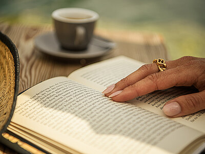 Hotel WINZER summer photoshoot on 14 July 2025 A woman is reading a book and drinking coffee by the natural pool at the Winzer Wellness Hotel