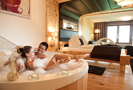 A couple enjoys a bubble bath in the Harmonie Suite at the Kuschelhotel Winzer on Lake Attersee