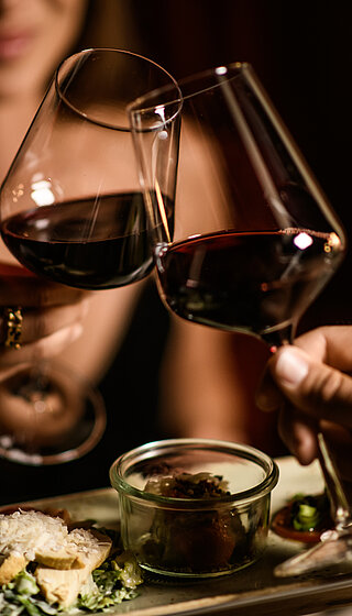 A woman with a glass of wine at the food-sharing table at the Adults Only Hotel Winzer