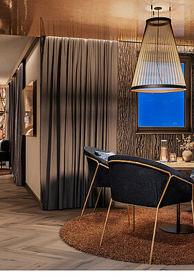 Luxuriöse Private Cinema Suite mit rundem Bett, elegantem Essbereich und kupferfarben glänzender Decke.